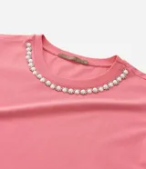 Blusa rosada de manga corta con cuello redondo decorado con una aplicación de perlas artificiales y strass a modo de collar.