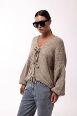 Saco tejido de punto con escote en V y cierre frontal mediante lazos decorativos. Presenta mangas largas amplias con puños ajustados y un calce relajado.