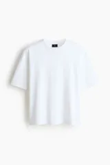 Remera blanca de algodón con corte oversized, hombros caídos, cuello redondo acanalado y mangas cortas amplias.