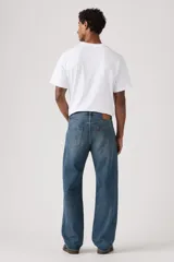 Jeans de corte holgado y tiro medio, con diseño clásico de cinco bolsillos y cierre de botones. Presentan un lavado azul medio con efecto desgastado en los muslos.