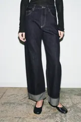 Jeans de tiro medio con corte baggy y pierna relajada. Presenta diseño de cinco bolsillos, cierre frontal con cremallera y botón, y bajo con vuelta marcada.