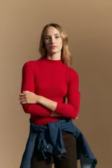 Polera de punto acanalado color gris, con cuello alto y mangas largas, de calce ajustado al cuerpo.