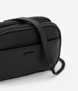 Cartera bandolera negra de poliuretano con tres compartimentos con cierre de cremallera y asa de cadena.