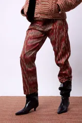 Pantalón de corte recto con largo al tobillo, confeccionado con una estampa geométrica sublimada en tonos marrón y rojo. Presenta tiro medio y un calce cómodo.