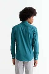 Camisa de manga larga color crema, con cuello camisero y botones frontales. Corte ajustado.