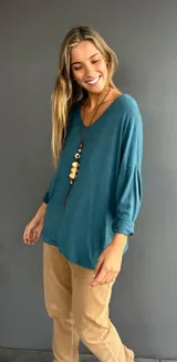 Jersey de punto color turquesa, con cuello en V, diseño oversize y mangas tres cuartos con dobladillo. Confeccionado en tejido liviano con caída fluida.