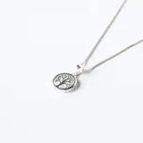 Conjunto de collar y aros a juego, elaborados en plata con dije circular que presenta un diseño de árbol de la vida sobre una base de nácar.