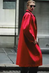 Trench largo ZARA Woman Collection de color rojo con cuello solapa, manga larga y bolsillos laterales ocultos. Presenta forro interior a contraste y cierre frontal con botones a presión.