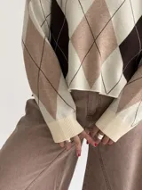 Sweater de punto con diseño de rombos en tonos marrón, beige y celeste, de corte holgado, cuello redondo y manga larga.