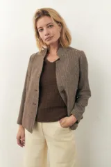 Chaqueta corta con cuello solapa, manga larga con coderas aplicadas, cierre frontal con botones y bolsillos ojal. Con forro.