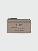Billetera Marc Jacobs The Top Zip Multi Wallet de cuero negro granulado, con cierre superior dorado y la inscripción "THE WALLET MARC JACOBS" grabada en relieve en el frente.