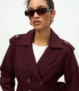 Campera de estilo trench corto en color bordó, con cuello solapa, cierre cruzado con botones, detalle de charreteras en los hombros, cintura elástica marcada y mangas largas con puños ajustados.