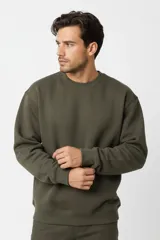 Buzo de cuello redondo color verde militar, de mangas largas con puños y dobladillo acanalados, y calce holgado.