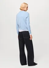 Sweater de punto fino mezcla de algodón y lana, color celeste, con cuello polo y cierre frontal de botones, de manga larga.