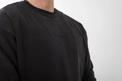 Buzo de cuello redondo con efecto stone wash, color gris oscuro. Presenta un diseño minimalista con bordado sutil en el pecho y detalle en la manga.
