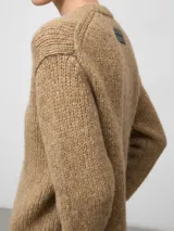 Cárdigan de punto en color camel, con cuello en pico, manga larga y cierre frontal mediante botones. Presenta un diseño de tejido grueso con acabado en canalé en los puños y el bajo.
