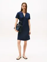 Vestido corto azul marino, tipo chomba, de corte evasé y manga corta. Presenta cuello en V con detalles en blanco y rojo, y logo bordado en la manga.