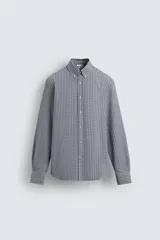 Camisa de corte regular fit confeccionada en tejido de algodón con efecto lavado. Presenta cuello abotonado, manga larga con puños abotonados, bolsillo en el pecho y cierre frontal con botones.