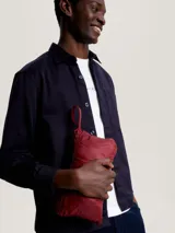 Chaleco acolchado rojo con cierre de cremallera, cuello alto y dos bolsillos laterales con cremallera. Tiene logo de Tommy Hilfiger bordado en el pecho.