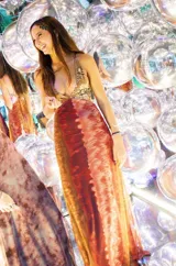 Vestido largo con escote en V, estampado en tonos rojizos y rosados, con un patrón ondulado. Presenta cut-outs laterales bajo el busto y breteles finos que se cruzan en la espalda.