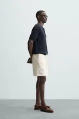 Bermuda de calce regular, color beige claro, confeccionada en tejido de mezcla de algodón con textura jacquard. Presenta cintura elástica ajustable con cordón, bolsillos frontales y un bolsillo trasero de vivo.