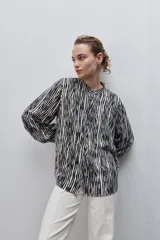 Camisa de calce amplio y fluido de viscosa liviana, con estampado de rayas verticales irregulares en blanco y negro, cuello mao, abotonadura frontal y mangas largas.
