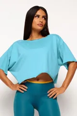 Remera corta de manga corta color celeste, con escote amplio en la espalda que se anuda en la parte inferior, dejando ver un top deportivo amarillo con tiras cruzadas.