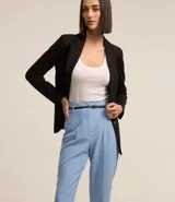 Pantalón carrot negro de sastrería, con bolsillos, pliegues y cinturón fino de cuero sintético.