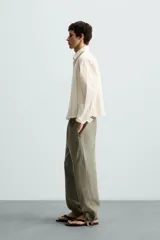 Camisa relaxed fit de manga larga con cuello solapa, confeccionada en tejido con mezcla de algodón. Presenta un estampado de rayas verticales en tonos beige, blanco y marrón. Incluye un bolsillo plastrón en el pecho, puños con botón y aberturas laterales en el bajo. Cierre frontal de botonadura.