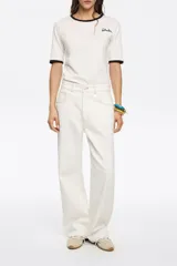 Pantalón vaquero de corte wide leg en color blanco. Presenta tiro medio, cierre frontal con botón y diseño clásico de cinco bolsillos.
