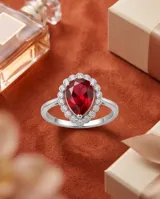 Anillo de plata con piedra central roja en corte gota, rodeada por circonias cúbicas.