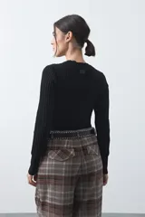 Sweater de tejido tipo rib, color negro, con cuello redondo y mangas largas. Presenta una textura acanalada y un ajuste al cuerpo.