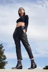 Pantalón sastrero negro de ecocuero con botamanga irregular, bolsillos delanteros y bolsillos ojal en la espalda.