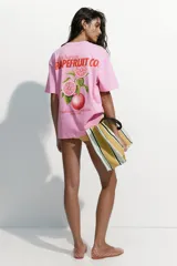 Remera oversized de punto de algodón color rosado, con hombros caídos, cuello redondo y pequeño texto estampado en el pecho.