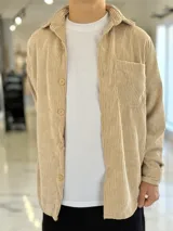Sobrecamisa de pana color beige, de manga larga, con cuello clásico, cierre frontal de botones y un bolsillo aplicado en el pecho.