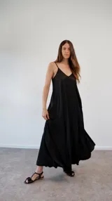 Vestido largo de satén negro, con diseño de solera, escote en V y breteles finos ajustables. Presenta un corte holgado y fluido.