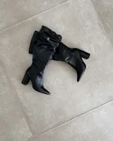 Bota de cuero color marrón con caña alta abullonada y taco cuadrado.