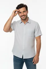 Camisa de manga corta color gris claro, con cuello camisero, cierre frontal con botones y un bolsillo ojal en el pecho.