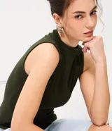 Musculosa básica de cuello alto, sin mangas, confeccionada en una mezcla de algodón, modal y elastano. Presenta un diseño ajustado y minimalista, ideal para uso diario.