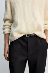 Pantalón de corte slim fit y color negro, confeccionado en tejido elástico. Cuenta con cintura elástica, trabillas, bolsillos frontales y cierre con cremallera y botón.