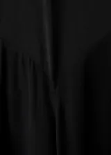 Vestido largo de fiesta color negro, con cuello alto, manga larga y diseño evasé. Presenta un corte en pico en la cintura y forro interior.