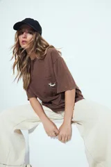 Remerón de manga corta color terracota con efecto gastado, silueta amplia y bolsillo aplicado con bordado de perro salchicha.