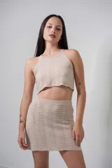 Top corto de tejido de punto calado color beige, con cuello halter y espalda descubierta.