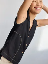 Camisa color beige claro sin mangas, con cuello camisero y cierre frontal con botones.