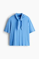 Top de punto suave de algodón, color celeste, con hombros caídos, mangas cortas y cuello tipo fular anudado al frente.
