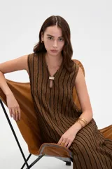 Vestido midi sin mangas de poliéster, color beige con rayas verticales negras, cuello en V y detalle de argolla metálica en el escote.