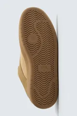 Zapatillas acordonadas color ocre, con suela de goma marrón con volumen.