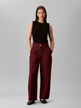 Pantalón chino de pierna ancha y talle alto Calvin Klein, color bordó, con cierre de doble botón y cremallera, bolsillos laterales y detalles de costura frontal.