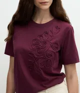 Remera de algodón color bordó con cuello redondo, mangas cortas y diseño de bordado floral en relieve en la parte delantera.