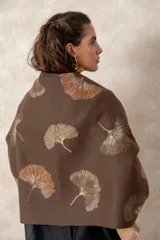 Pashmina reversible de textura suave y caída fluida, con diseño estampado de hojas de ginkgo biloba. Presenta un lado con fondo oscuro y otro con fondo claro, finalizando en ambos extremos con flecos cortos deshilachados.